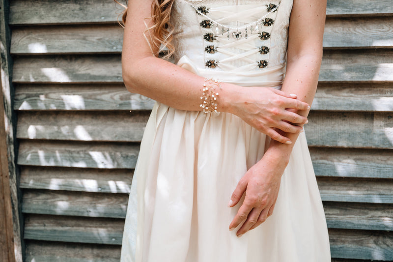 Elegantes Armband mit Perlen und funkelnden Steinchen auf einem goldenen Draht, perfekt für festliche Anlässe.